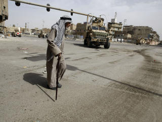 SPENT En gammel mann passerer en vaktpost i bydelen. Mange frykter det er stille f�r stormen. Foto: AFP/AHMAD AL-RUBAYE/SCANPIX