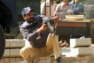 SKUDDVEKSLING: En pakistansk politimenn skyter mot Taliban-soldatene som forskanset seg inne p� politih�yskolen. Foto: Scanpix
