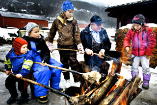ULLA: Bestefar Ivar L. L�ne (69) l�rer barnebarna hvordan man svidde smalahovene f�r de fikk maskinell produksjon. Fra venstre Henrik(3), Hanna(11), Marte (10) og Kari(7).   foto: Ole C. H. Thomassen