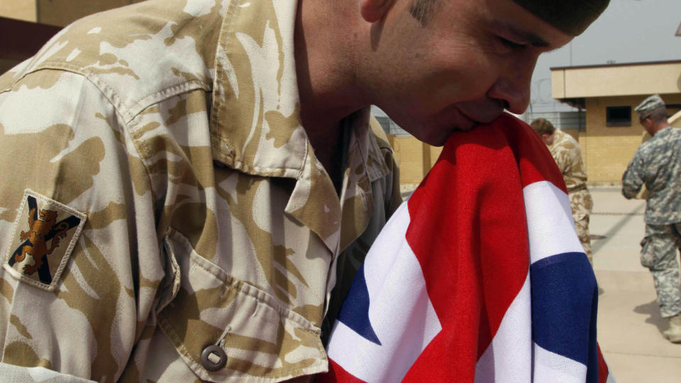 KYSSET FARVEL: En britisk soldat kysset Union Jack farvel under en sermoni p� den n� amerikanske basen i Basra i Irak. Innbyggeren i byen frykter at amerikanerne vil g� hardere fram enn britene. Foto: Nabil al-Juran/AP