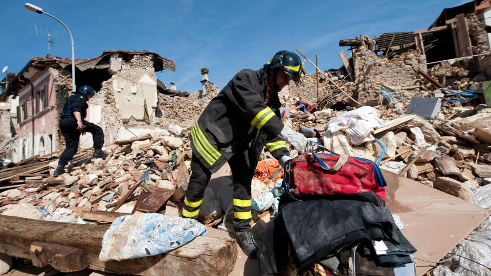 REDNINGSARBEID: Brannmenn henter ut eiendelene til noen av de omkomne etter jordskjelvet i Italia. N� meldes det om funn ogs� av levende mennesker under ruinene. Foto: Christophe Simon/AFP/Scanpix