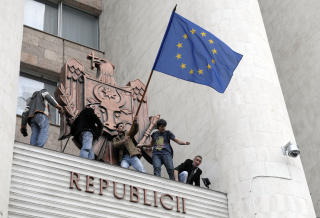 VIL VESTOVER: Moldovere veiver EU-flagget fra avsatsen over inngangen p� parlamentet. Foto: VADIM DENISOV/AFP