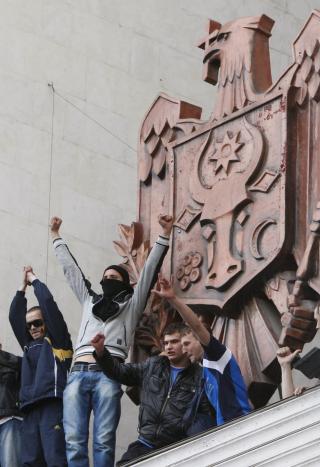 NASJONALSYMBOLET: Demonstranter tok seg opp p� taket p� parlamentsbygningen 7. april, hvor de stilte seg opp ved siden av nasjonalsymbolet. Foto: REUTERS/Gleb Garanich