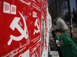 PLAKATKAMP: Frivillige for Liberaldemokratene klistrer sine plakater over Kommunistpartiets i hovedstaden Chisinau. Foto: AP/John McConnico