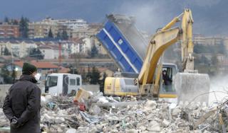 OPPRYDNING: En gravemaskin g�r gjennom ruinene. Foto: SCANPIX