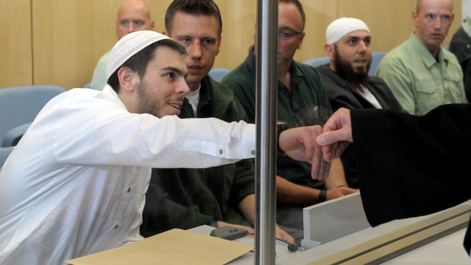 HILSTE P� FORSVAREREN: De tiltalte sitter bak skuddsikkert glass. Her hilser tiltalte  Daniel Schneider p� forsvareren sin. Foto: REUTERS/Federico Gambarini/Pool/SCANPIX