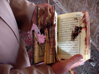 BLODBAD: En mann viser fram en blodig koran, funnet i en moske i byen Dhuluiyah, hvor fire mennesker ble drept i et selvmordsangrep i g�r. Foto: AFP PHOTO/Mahmud Saleh/Scanpix