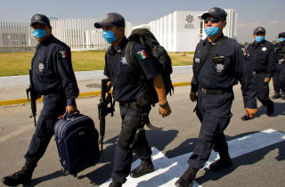 BESKYTTER SEG: Disse politifolkene bruker munnbind som beskyttelse. Foto: AFP PHOTO/Alfredo Estrella/Scanpix
