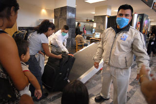 TIJUANA: Flyplassansatte med masker sjekker passasjerer som har kommet med lokalfly fra Mexico by. Foto: AFP PHOTO/David Maung/SCANPIX