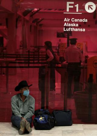 152 D�DE: En turist venter utenfor Benito Juarez internasjonale flyplass i Mexico City, i kledd ansiktsmaske. 152 mennesker skal v�re d�de som f�lge av viruset som har rammet landet. Foto:  REUTERS/Henry Romero