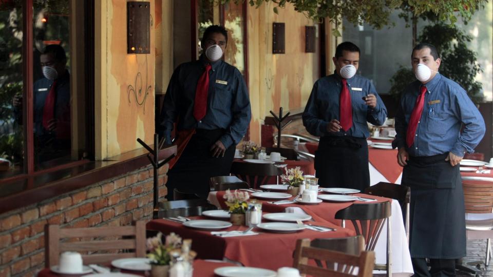 MASKERTE SERVIT�RER: Ordf�reren i Mexico by sier at smitten ser ut til � ha stabilisert seg. Han vurderer n� � lette p� sikkerhetstiltakene i byen. REUTERS/Henry Romero/SCANPIX