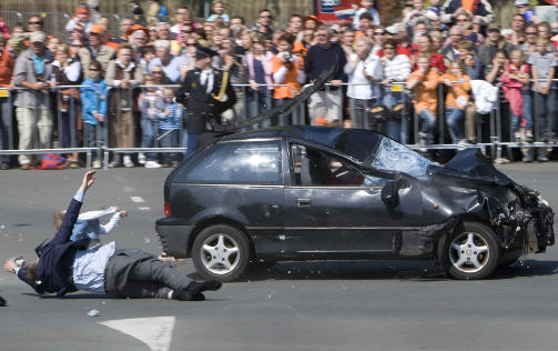 SKREKKSCENER: To personer meies ned av den l�pske bilen, som ubekrefta meldinger sier var p� vei mot en �pen buss hvor dronning Beatrix satt. Foto: SCANPIX/AP Photo/Robin Utrecht
