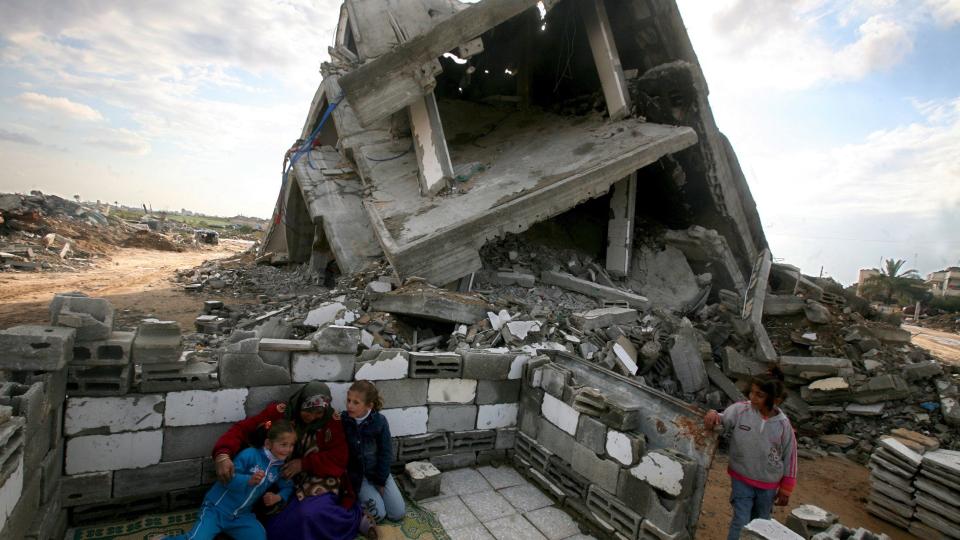 STORT BEHOV FOR HJELP: Khadra Abed Rabo sitter med sine nieser og nev�er utenfor famliens �delagte hus i flyktningeleiren Jabaliya nord p� Gaza-stripen. Selv om krigen er over er n�den og behovet for hjelp enormt. Foto: Scanpix