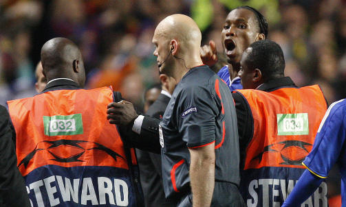 FIKK BESKYTTELSE: Tom Henning �vreb� m�tte ha beskyttelse av vaktene for � holde Didier Drogba unna etter kampen. Foto: AP