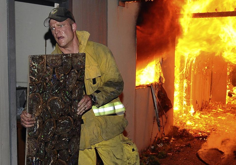 BRENNER NED: Brannmann Andy Klein fors�ker � redde et maleri fra et brennende hus i Santa Barbara, California. Minst 13 000 mennesker er p� flukt fra brannene i omr�det, og et tjuetalls hus er blitt redusert til rykende ruiner. Foto: REUTERS/SCANPIX