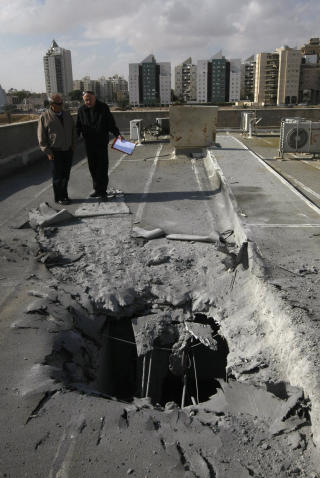 RAKETTANGREP: Israelere st�r ved stedet der et palestinsk rakettangrep har sl�tt ned i byen Beersheva. De daglige rakettangrepene var en hoved�rsakene til at den israelske offensiven ble innledet. Foto: AFP PHOTO/MENAHEM KAHANA/SCANPIX