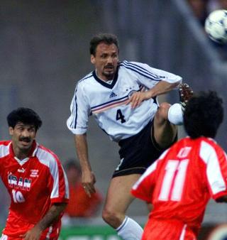 BARTEMESTERE: F� fotballspillere p� h�yeste niv� har hatt mer karakteristiske barter enn Tysklands J�rgen Kohler (i midten) og Irans Ali Daei (t.v.). Her er de to samlet i ett og samme magiske barte�yeblikk. Foto: Michael Probst, AP/Scanpix