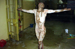 M�TTE POSERE: En naken irakisk fange innsmurt i hvite og brune substanser i Abu Ghraib. Foto: SCANPIX
