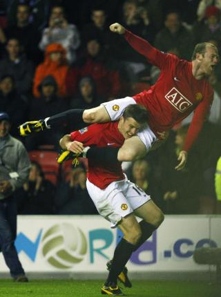 VILL JUBEL: Wayne Rooney p� rask vei ned fra skuldrene til Michael Carrick etter at sistnevnte sikret United seieren mot Wigan fire minutter f�r full tid. Foto: Phil Noble, Reuters/Scanpix