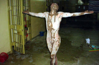 M�TTE POSERE: En naken irakisk fange innsmurt i hvite og brune substanser i Abu Ghraib. Foto: SCANPIX