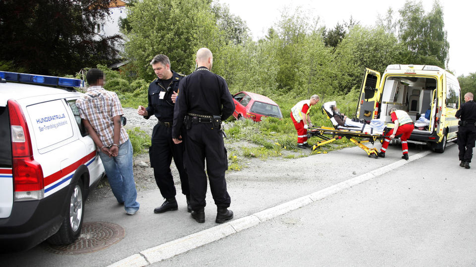 FLIRER: Mens kvinnen f�res inn i ambulansen, st�r 29-�ringen (t.v) og flirer. I bakgrunnen st�r bilen han brukte til � meie ned sin eks. Foto: Tom �sthus / Dagbladet