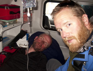 I AMBULANSEN: Etter en flere timer lang Jeep-tur til Nepal-grensa, ble Tr� plukket opp av ambulanse. Her sover han, med frostskader i ansiktet, mens legen Erichsrud v�ker over ham.  Foto: www.everest09.no