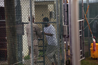 BAK GJERDET: En uigursk Guantanamo-fange mottar instrukser fra en fangevokter mens han fortsatt satt innesperret. Foto: AFP PHOTO/Brennan Linsley/Scanpix