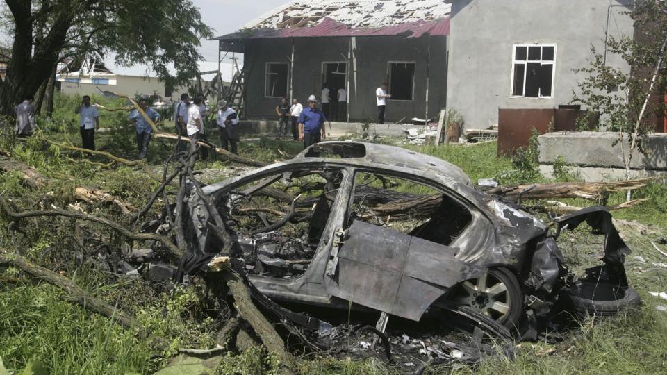 SELVMORDSBOMBERENS BIL: ligger utbrent p� siden av veien. Etterforskere arbeider p� �stedet. Huset i bakgrunnen fikk knust vindusrutene og �delagt taket under eksplosjonen. Foto: REUTERS/Stringer (RUSSIA POLITICS CRIME LAW DISASTER)