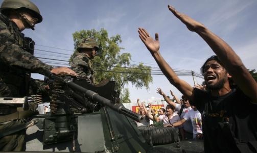 HINDRER KUPP: St�ttespillerne til Honduras president hindrer milit�re kj�ret�y i � komme forbi. Politiet skal ha skutt t�regass mot folkemengden. Foto: REUTERS/Oswaldo Rivas