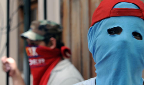 DEMONSTRANTER: Maskerte demonstranter utenfor presidentpalasset i den honduranske hovedstaden Tegucigalpa mandag. (Foto: SCANPIX)