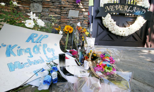 FANSEN S�RGER: Inngangspartiet utenfor Neverland-ranchen er full av blomster og hilsner fra fansen. Fredag skal Jacksons b�re vises fram for offentligheten inne p� Neverland. Foto: Scanpix.