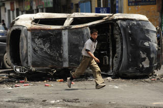 UTBRENT: En gutt g�r forbi en bil som ble p�satt under g�rsdagens sammenst�t. Foto: AFP PHOTO/Peter PARKS/SCANPIX