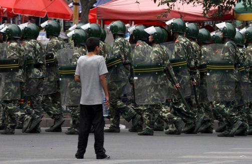 GATER FULLE AV SOLDATER: En lokal gutt ser p� mens kinesiske soldater patruljerer gatene i Urumqi i dag mandag. Foto: REUTERS/David Gray