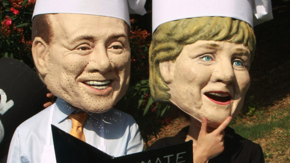 MANGE KOKKER, LITE MATNYTTIG: To aktivister som skal forestille m�tevert Silvio Berlusconi og Tysklands Angela Merkel demonstrerer mot G8-m�tet. Foto: AP Photo/Sandro Pace/SCANPIX