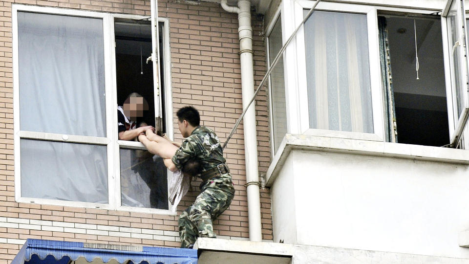 REDDET JENTA: Den 22 �r gamle brannmannen, kledd i milit�runiform, klarte � redde jenta ut av farens grep. Foto: REUTERS/China Daily/Scanpix