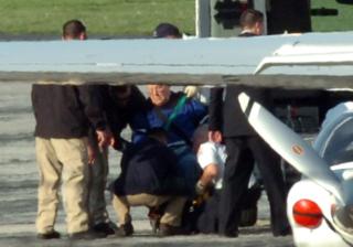 L�FTES OM BORD I FLYET:  John Demjanjuk sitter i rullestol og blir her l�ftet om bord i flyet som tok han fra USA til Tyskland. Et mindre fly st�r i forgrunnen. Foto: REUTERS/Ron Kuntz/Scanpix