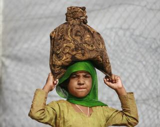 P� VEI HJEM: Ei pakistansk jente b�rer bagasje til en av bussene som skal bringe flyktningene tilbake til Swat-dalen. To millioner mennesker ble drevet p� flukt som f�lge av kampene mellom regjeringsstyrker og Taliban. N� vil myndighetene ha dem hjem igjen. Foto: REUTERS / Ali Imam / SCANPIX