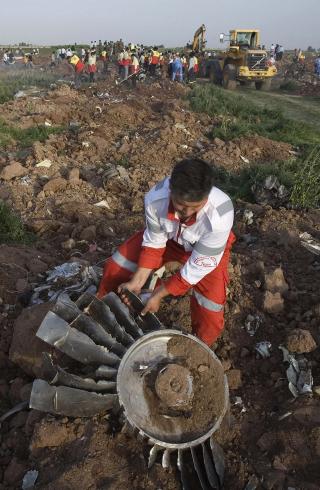 VIFTE: En hjelpearbeider henter en vifte fra flyet som styrtet vest for den iranske hovedstaden Teheran i g�r. Foto: REUTERS/Morteza Nikoubazl