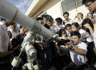 F�LGER MED: Vietnamesiske studenter og l�rere samler seg rundt et teleskop ved universitetet i Hanoi. Foto: CHITOSE SUZUKI/AP/SCANPIX