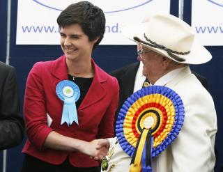 KONSERVATIV: Konservative Chloe Smith (27) begynner ikke i jobben i Parlamentet f�r de folkevalgtes ferie er slutt i oktober. - Jeg vil ikke hoppe av her og dra for � leve p� frynsegoder de neste tre sommerm�nedene, bedyrer hun. Her f�r hun gratulasjoner etter valgseieren fra representanten for Official Monster Raving Loony Party, Howling Laud. Laud fikk 144 stemmer i suppleringsvalget. Foto: REUTERS / Luke MacGregor / SCANPIX
