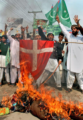 MUHAMMED-KARIKATURENE: Pakistanske fundamentalister brenner en dukke som skal forestille Fogh Rasmussen og det danske flagget for � markere sin motstand mot at Muhammed-tegningene ble trykket p� nytt. Foto: AP Photo/Khalid Tanveer/SCANPIX