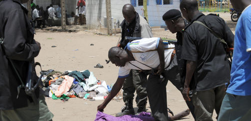 DREPT: En lokal politimann unders�ker et antatt medlem av Boko Haram som er blitt skutt. I g�r ble lederen av sekten skutt mens han var i politiets varetekt. Foto: AFP PHOTO/PIUS UTOMI EKPEI/SCANPIX
