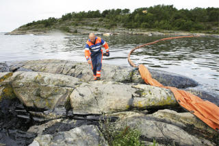 REDNINGSARBEID: Gunnar Egelien i Kystverket jobber febrilsk med � legge ut oljelenser i det rammede omr�det. Foto: PEDER GJERS�E/EPA/SCANPIX