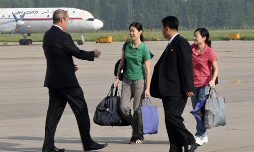  P� VEI HJEM:  De to l�slatte amerikanske journalistene p� rullebanen i Pyongyang - p� vei ombord i et fly som skal bringe dem til Los Angeles via Tokyo. Foto: REUTERS/XINHUA/SCANPIX.