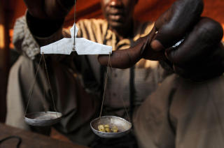 VERDT SIN VEKT I GULL: En handelsmann veier opp gull p� et marked 25 km nord for Bunia. 90 prosent av gullet som hentes ut i omr�det smugles over grensen, og finansierer den grufulle borgerkrigen i landet. Foto: AFP PHOTO / LIONEL HEALING /Scanpix