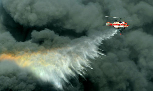 FRYKTER INFERNO: Et helikopter fors�ker � slukke brannen, etter at arbeiderne satte fyr p� bildekk for � spre svart r�yk over fabrikkomr�det. P� fabrikkens lakkverksted er det lagret flere tusen liter brennbar v�ske. Foto: AFP PHOTO / AUM JUNG-SEOK/SCANPIX