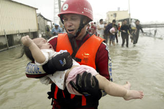 VERSTE P� 50 �R: En redningsarbeider hjelper en baby i Taiwan. Landet opplevde de verste oversv�mmelsene p� 50 �r da tyfonen Morakot traff i helga. Foto: AP/SCANPIX