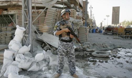 FLERE ANGREP: En irakisk politimann holder vakt i Amil-bydelen i Bagdad, der minst sju arbeidere ble drept da en bombe gikk av mandag morgen. Minst 45 personer ble drept i ulike bombeangrep i Irak mandag. Foto: Scanpix