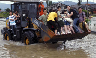 ENORME FLOMMER: Evakuerte mennesker f�r skyss av en bulldoser i �stkinas Zhejiang-provins. Foto: AP Photo