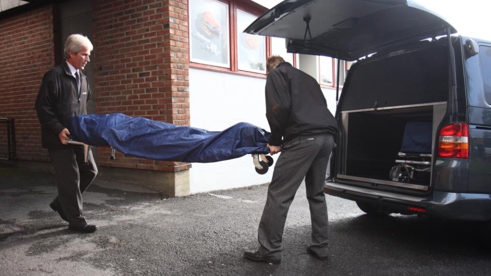 BAR UT LIKET: Ved 08:30-tiden i dag ble liket av kvinnen (50) b�ret ut fra leiligheten av to menn fra et begravelsesbyr�. Da hadde kriminalteknikere unders�kt stedet siden mannen hennes ble p�grepet i 01.30-tiden i natt. Foto: Svein Gustav Wilhelmsen